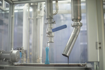 Liquid chocolate. Candy production. Chocolate flowing out of a pipe.