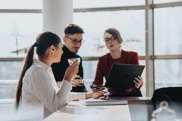 Three business employees engage in discussion at an office kitchen, fostering collaboration and teamwork. They interact over coffee, creating a casual yet professional atmosphere for innovative ideas