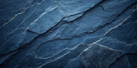 Dark blue slate rock texture background with rough and cracked stone layers, creating a natural,...