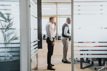 Two business people engage in a strategic meeting in a contemporary office with glass walls. The atmosphere is sophisticated and focused, highlighting collaboration and corporate environment.