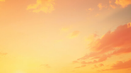 Obraz premium A soft, golden sunset sky blending into warm shades of orange and pink, creating a peaceful and tranquil beach evening atmosphere with gentle clouds and calm waters.