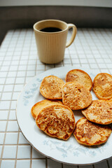coffee and pancakes on plate on kitchen table, breakfast on sunny morning. healthy eating, vegetarian. top view of food. a nutritious lunch, delicious and balanced.