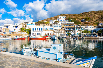 Colorful fishing boats anchoring in Katapola port with white Greek houses in background, Amorgos...