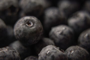 a close-up photograph of a cluster of blueberries. The berries are tightly packed together, filling the frame almost entirely. The dominant color is a deep, dusty blue