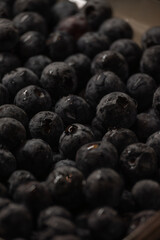 a close-up shot of a collection of blueberries. The berries are densely packed together, filling the frame. Many of the blueberries have small droplets of water on their surfaces