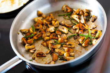 Delicious champignon mushrooms with asparagus fried in frying pan