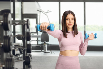 Beautiful young female exercising with dumbbells