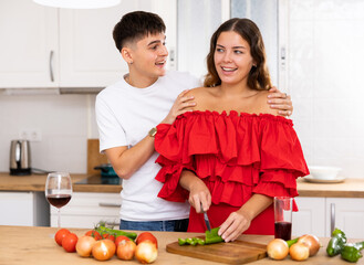 Happy family couple cooking healthy vegetable salad together in comfy home kitchen