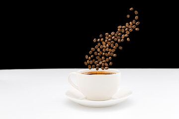 A cup of coffee. Smoke from coffee beans over a cup. Black and white background.
