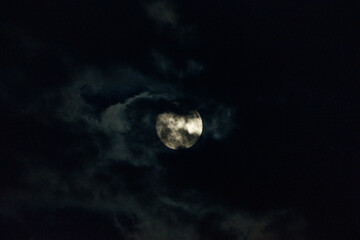Full moon partially obscured by clouds at night.  A celestial sight.