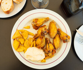 Roasted chicken wings french fries on a plate cooked in a cafe