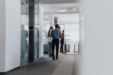 Fototapeta premium Business people engaged in conversation in a sleek, modern office hallway, reflecting collaboration and corporate interactions.