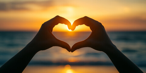 Sunset over the ocean viewed through hands forming a heart shape on a warm evening. Valentines Day