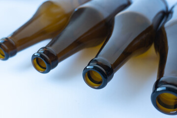 Four brown glass beer bottles lie with their necks facing the camera, creating a sense of depth in...