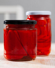 Homemade canned red bell peppers on wooden table