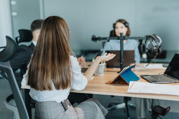 A diverse team of people engaged in a meeting with laptops and headsets in a contemporary office. The focus is on collaboration and communication among multiracial employees.