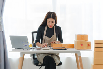 Focused Female Entrepreneur Managing Online Orders: A young, determined businesswoman meticulously...