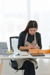 Small Business Owner Packing Orders: A young entrepreneur, focused and determined, carefully packs...