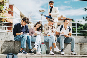 A group of high school students working together on assignments while sitting outdoors. A professor...