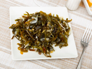 Pickled kelp salad with chopped onions on plate with plum vinegar dressing. Chinese cuisine ..