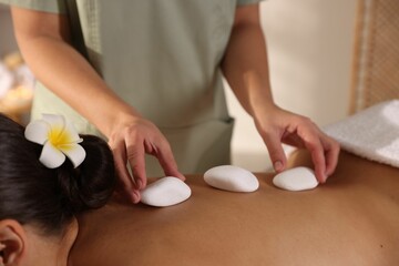 Woman receiving hot stone massage in spa salon, closeup
