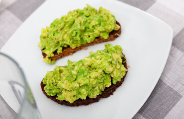 Appetizing toast with guacamole served on plate for breakfast