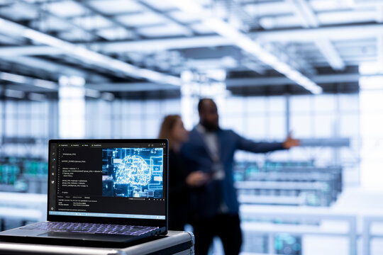 Focus on AI software on laptop in front of team of admins programming in AI data center. Close up of notebook in high tech server hub workspace used by workers upgrading artificial intelligence system