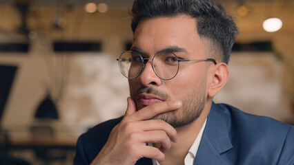 Pensive guy Arabian Indian business man thinking looking at camera close up male thoughtful puzzled...