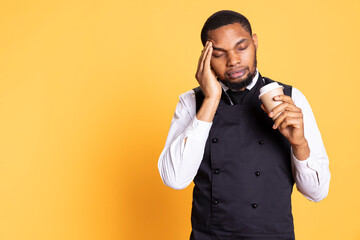 Restaurant employee dealing with a painful headache while he serves clients, carrying a cruet set for excellent customer satisfaction. Unwell waiter working in pain with migraine.