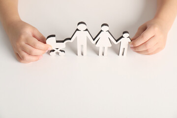 Adoption concept. Kid with cutout of family at white background, closeup. Space for text