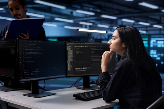 Software developer reconfiguring server farm to optimize it for data processing requirements of customers. Indian woman ensuring data center equipment operates efficiently - Powered by Adobe