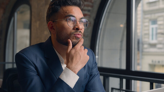 Thoughtful puzzled businessman Arabian Indian man thinking male guy employer worker think idea business plan strategy ponder consider doubt choose remember decide search deep thought question indoors