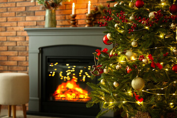 Beautiful decorated Christmas tree near fireplace at home, closeup. Space for text