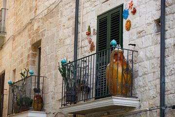 Traditional Italian Balcony with Ceramic Pots and Shutters on Stone Building in Southern Italy
