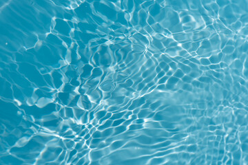 Blue water with ripples on the surface. Defocus blurred transparent blue colored clear calm water surface texture with splashes and bubbles. Water waves with shining pattern texture background.