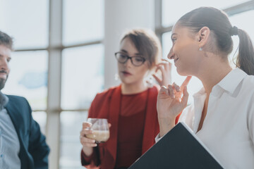 A group of business coworkers engaging in a focused conversation in a modern office setting. The atmosphere is collaborative, highlighting teamwork and communication among business people