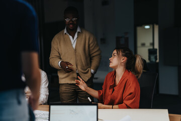 A multiracial group of business colleagues engage in a brainstorming session, exchanging ideas and solutions while working late to meet project deadlines.