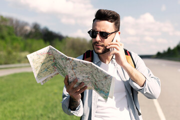 Stressed male tourist with map standing on roadside, speaking on mobile phone, cannot catch car or...