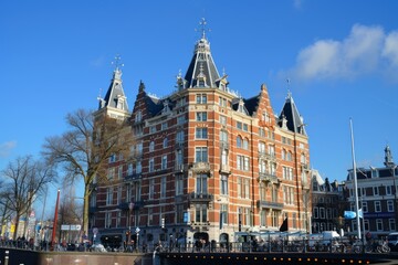 Fototapeta premium Traditional dutch architecture building standing on amsterdam canal on a sunny day with clear blue sky