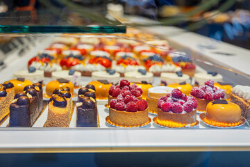 Assorted colorful pastries with raspberries and chocolate on display. Concept of bakery sweets, desserts