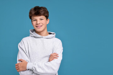 Portrait of happy teenage boy on light blue background, space for text