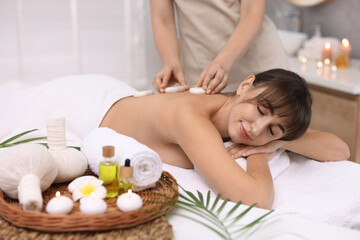 Obraz na płótnie Canvas Young woman receiving hot stone massage in spa salon