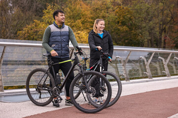 Fototapeta premium Beautiful happy couple with bicycles spending time together outdoors, space for text