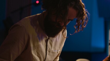 Musician composer playing midi controller synthesizer in professional studio, composing music on mixing console. Artist performing on piano electronic keyboard in control room. Camera A.