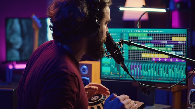 Music producer singing at home studio microphone to record songs, editing and adjusting volume levels in post production. Audio engineer conducts recordings of vocals, mixing console. Camera A.