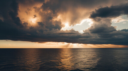 Naklejka premium Dramatic sunset over a calm ocean, with dark storm clouds and golden rays illuminating the water surface.