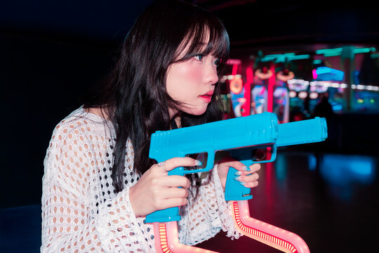 Asian Gen Z girl enjoying vibrant arcade with retro games