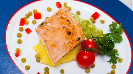 Tasty fried trout fillet with mashed potatoes, guacamole, tomatoes and greens on plate