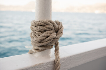 A rope is tied in a knot on the deck of a sea vessel. Close-up of a sea knot. Ship rope