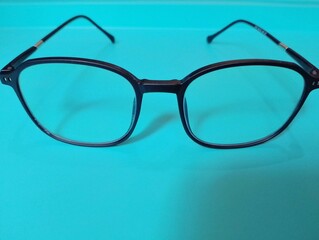 A pair of black-framed glasses casts a shadow on a white surface.